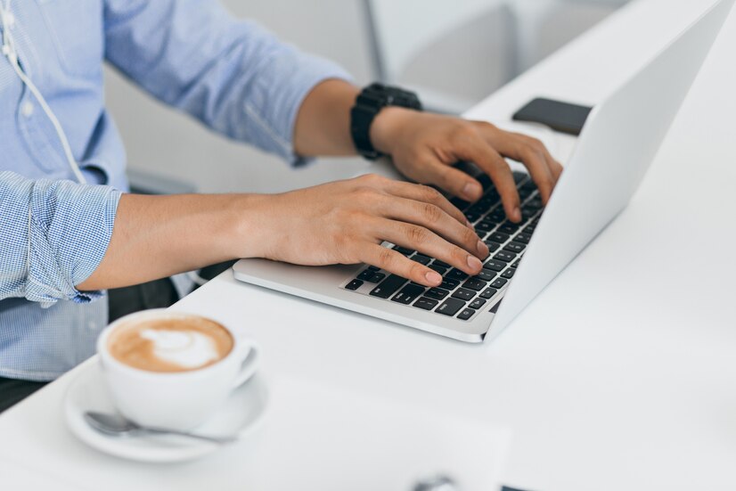 Person typing on a laptop with a cup of coffee